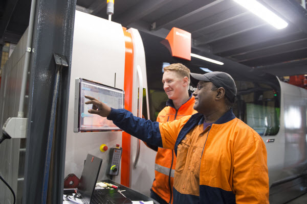 Two men worker operating equipment through a computer