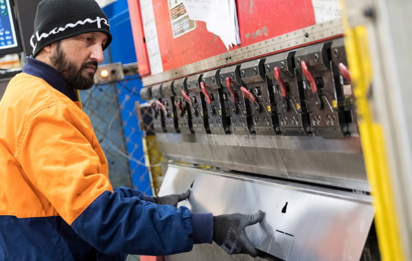 Man using machinery to bend metal plate