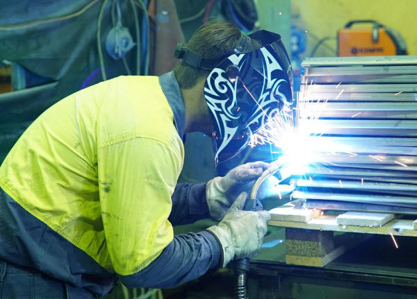 Man wearing full safety welding mask while welding a steel