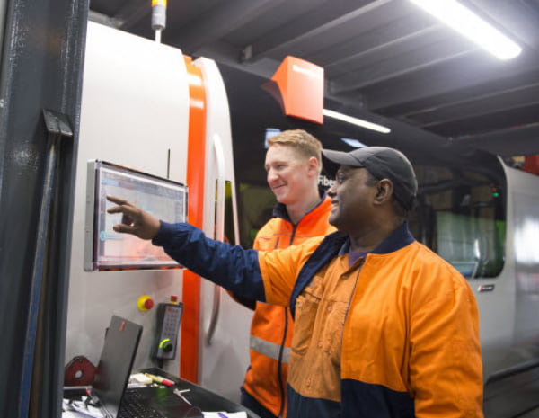 Two men worker operating equipment through a computer