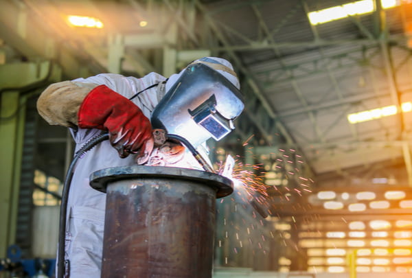 Man welding steel pipe by mig in factory