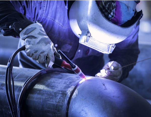 Worker welding metal piping using tig welder