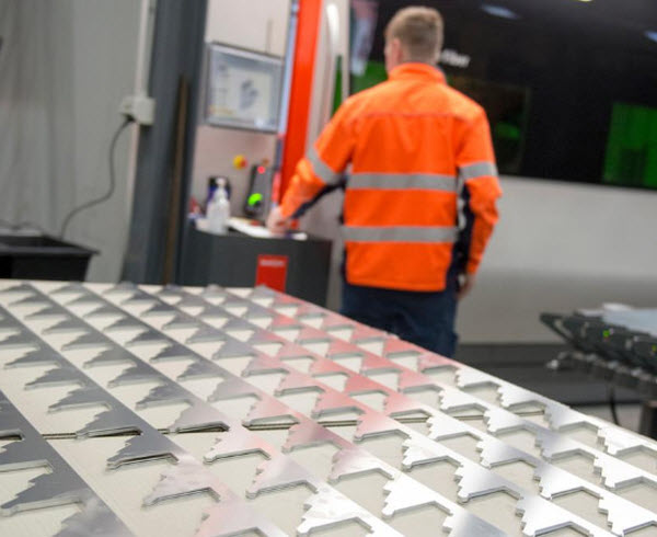 Metal cuttings on a table inside a room with a man checking the machine