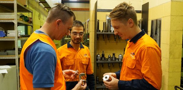 Colleagues wearing orange uniform holding the steel metal parts products