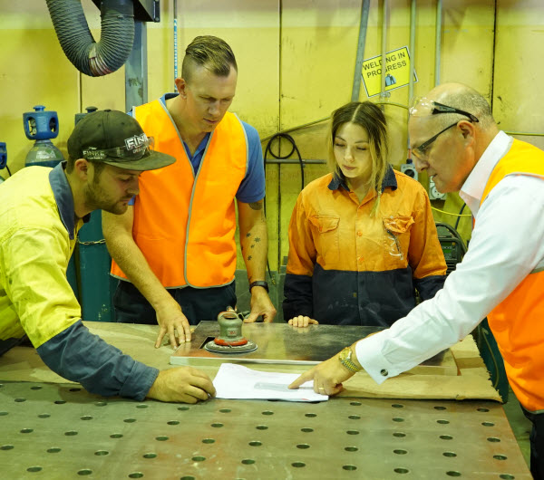 Busy geoup of engineers wearing orange uniform discussing the design