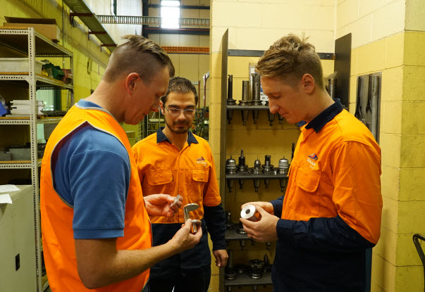 Colleagues wearing orange uniform holding the steel metal parts products
